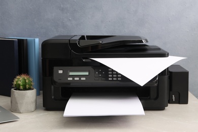 New modern printer on grey table at workplace