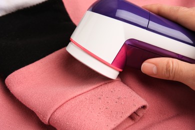 Photo of Woman using modern fabric shaver on sweater with lint, closeup