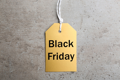 Photo of Blank golden tag on light grey stone background, top view. Black Friday concept