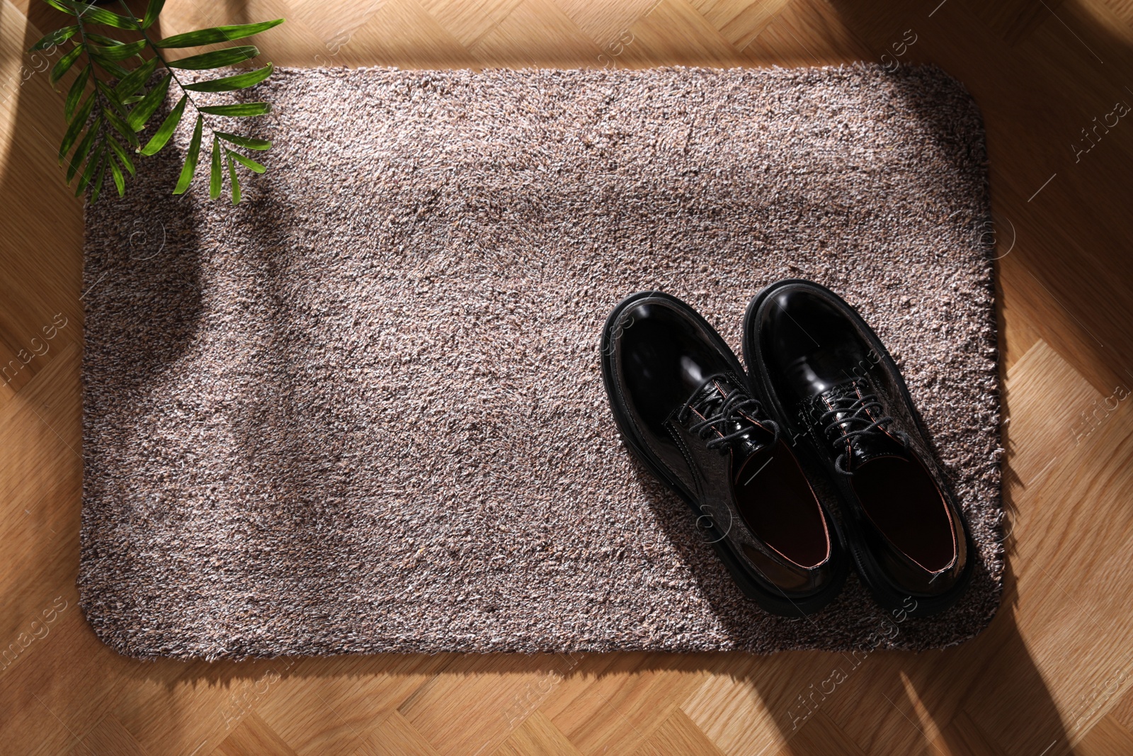 Photo of Stylish door mat with shoes on floor, top view