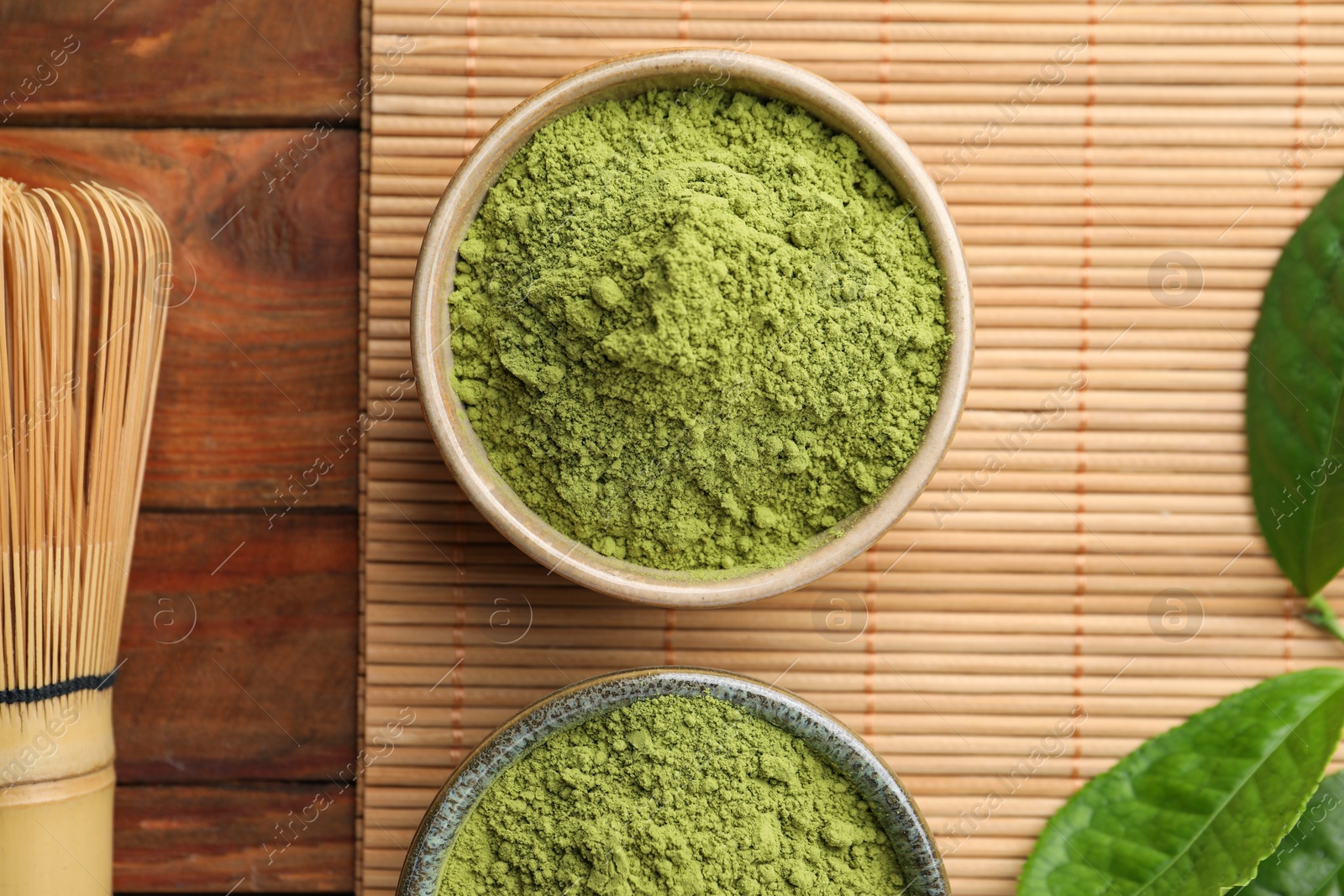 Photo of Green matcha powder and bamboo whisk on wooden table, flat lay