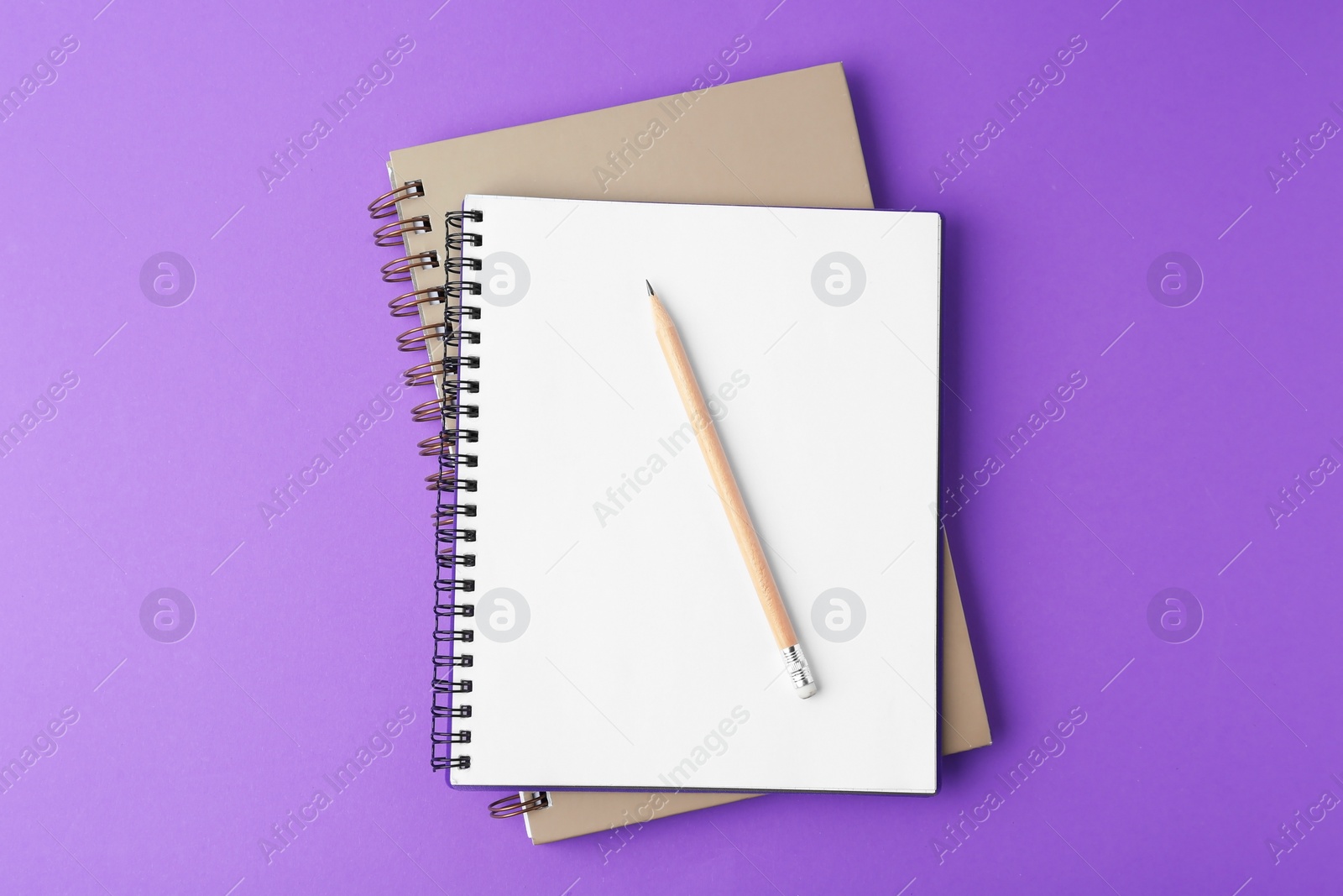 Photo of Notebooks with pencil on purple background, top view