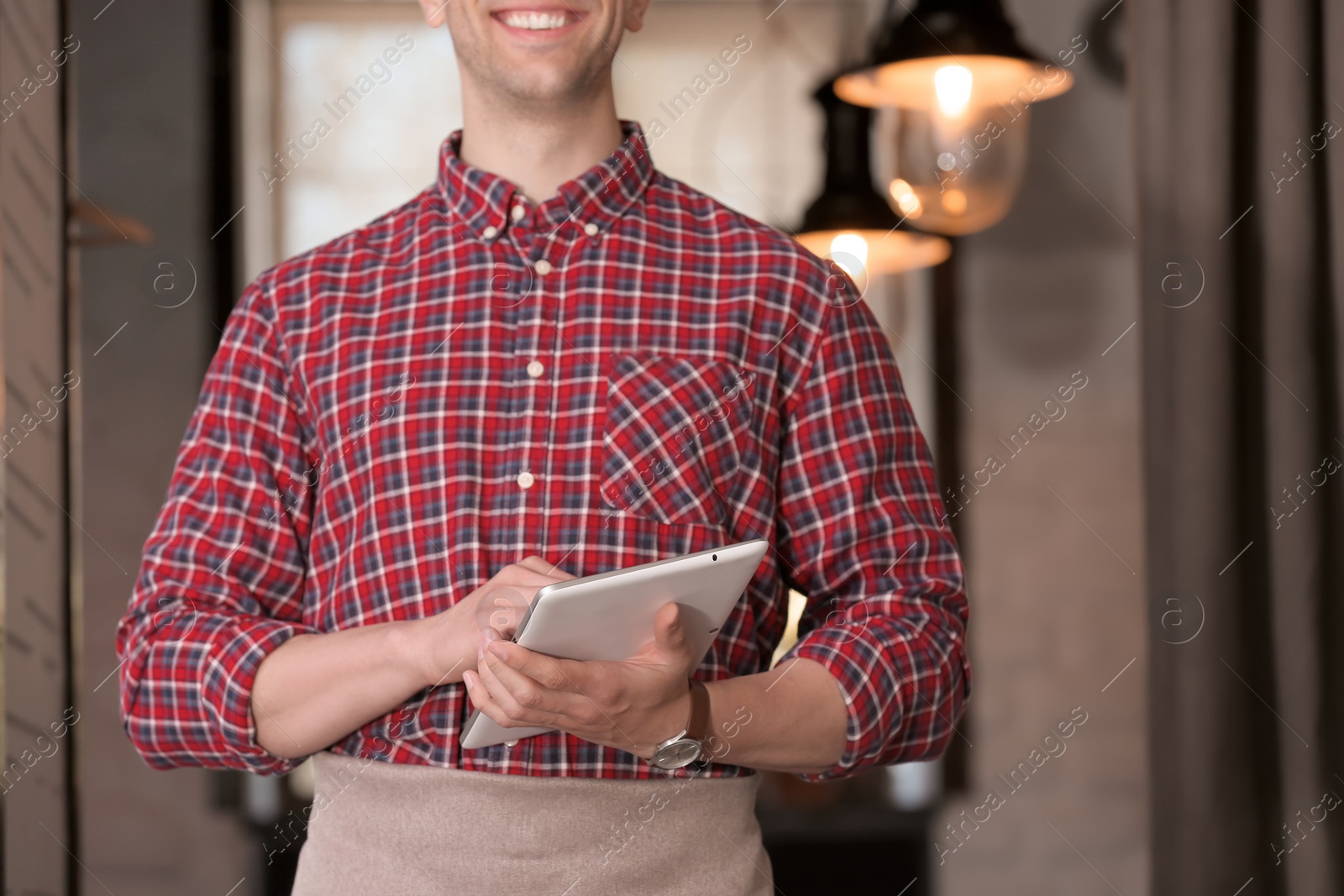 Photo of Young waiter with tablet computer at workplace