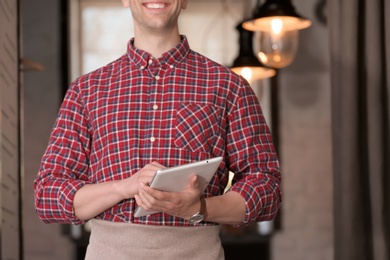 Photo of Young waiter with tablet computer at workplace