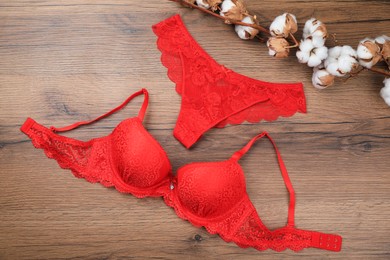 Photo of Elegant red women's underwear and cotton flowers on wooden background, flat lay