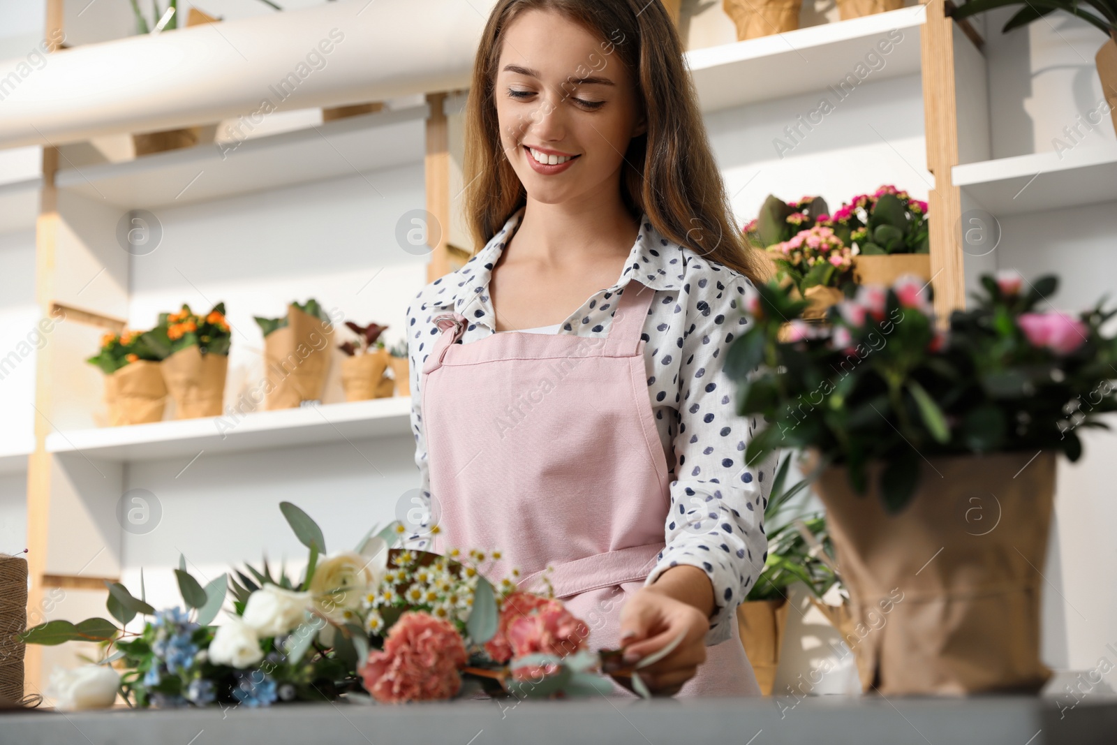 Photo of Florist making bouquet with fresh flowers at table in shop