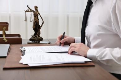 Lawyer working with documents at wooden table indoors, closeup
