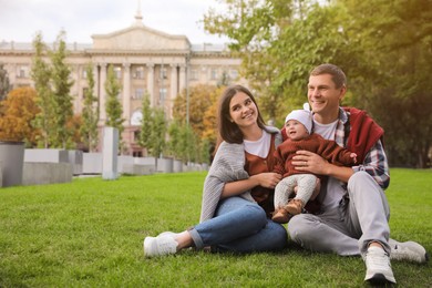 Happy parents with their adorable baby on green grass in park