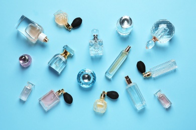 Flat lay composition with different perfume bottles on light blue background
