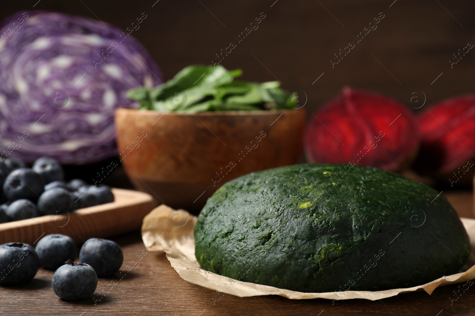 Photo of Dough painted with natural food coloring and ingredients on wooden table, closeup