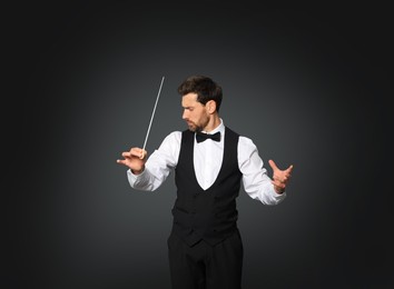 Professional conductor with baton on black background