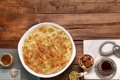 Delicious sweet baklava served on wooden table, flat lay