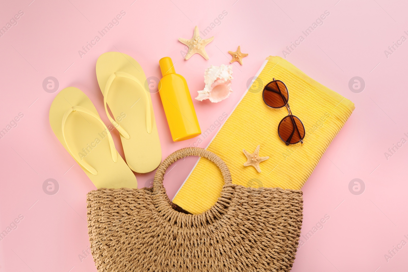 Photo of Stylish bag with beach accessories on pink background, flat lay