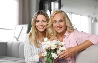 Photo of Young woman congratulating her mother in living room