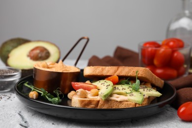 Photo of Delicious sandwich with hummus and vegetables on white textured table, closeup