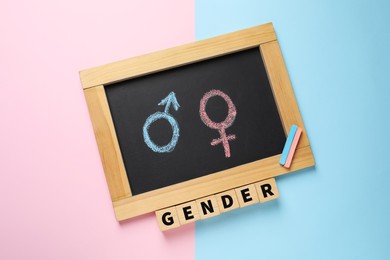 Photo of Word Gender and chalkboard with symbols on color background, top view