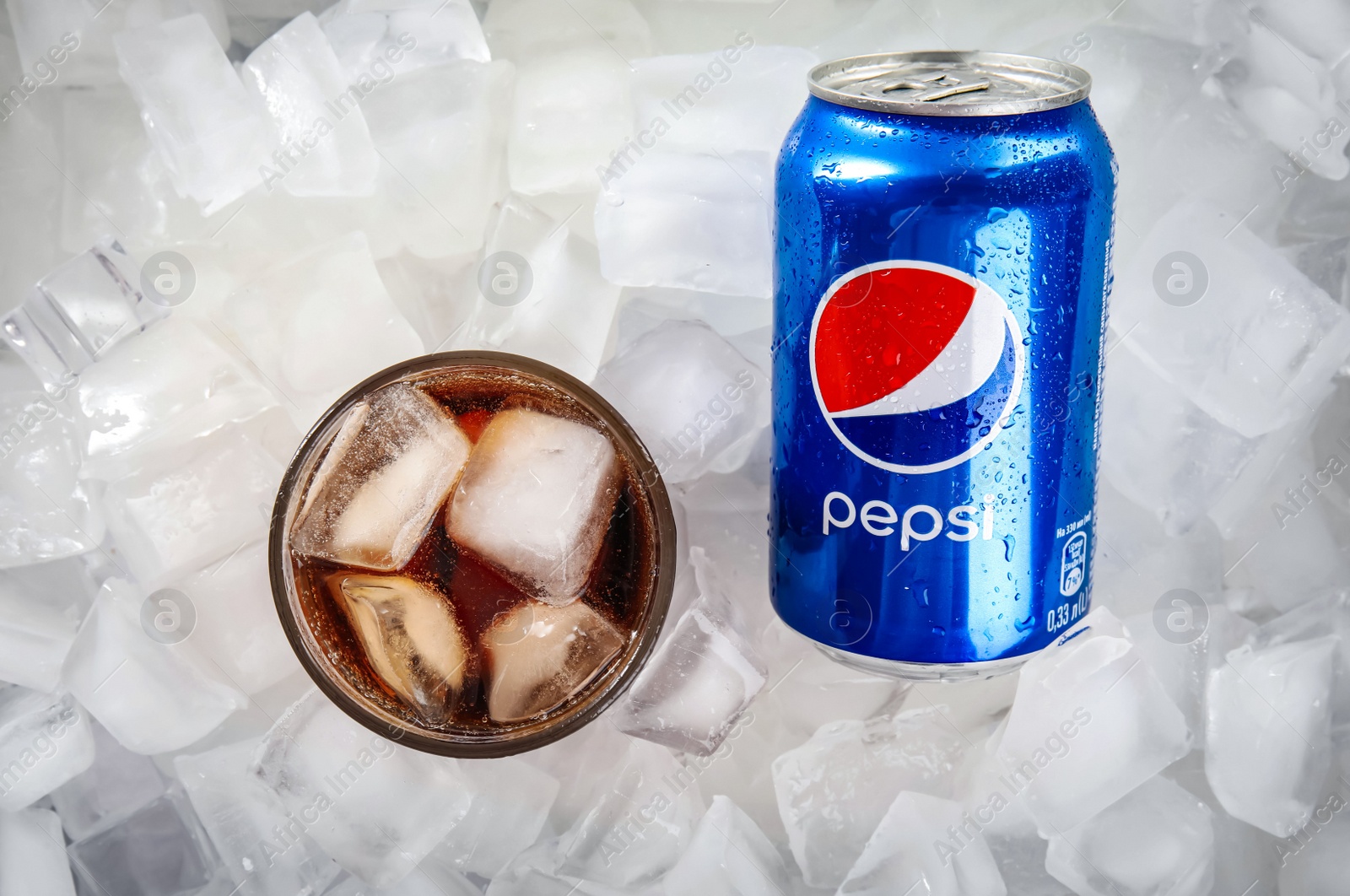 Photo of MYKOLAIV, UKRAINE - FEBRUARY 11, 2021: Glass of Pepsi and can on ice cubes, flat lay