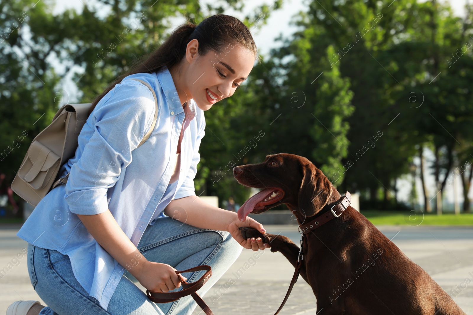 Photo of Young woman with her German Shorthaired Pointer dog on city street