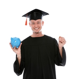 Portrait of young graduate with piggy bank and coin on white background
