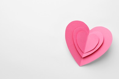 Photo of Pink paper hearts on white background, top view. Space for text