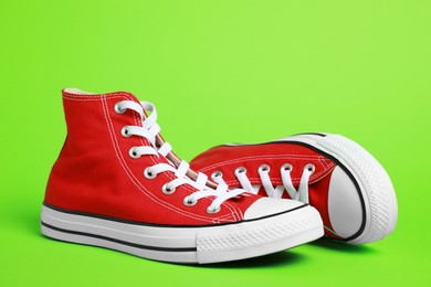 Photo of Pair of new stylish red sneakers on light green background