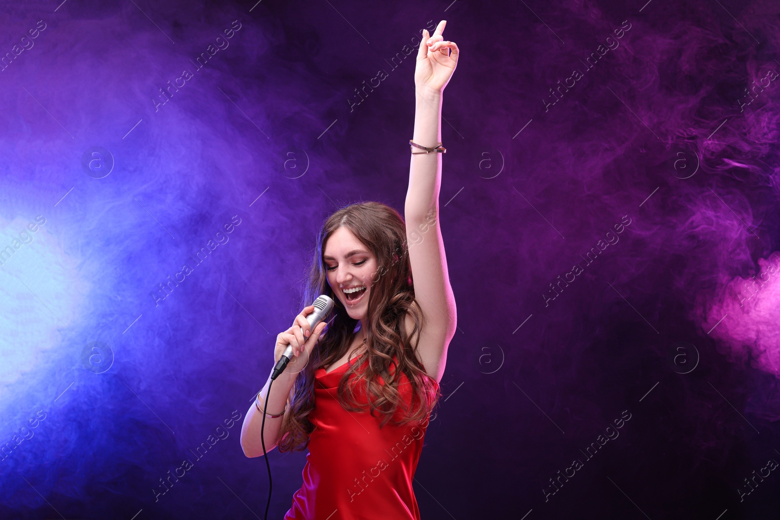 Photo of Beautiful woman with microphone singing in color lights