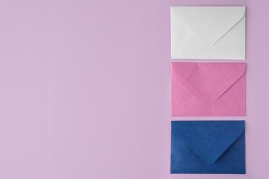 Colorful paper envelopes on pink background, flat lay. Space for text