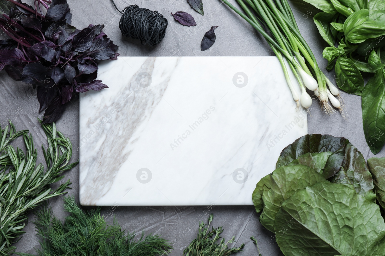 Photo of Different herbs and marble cutting board on grey table, flat lay. Space for text