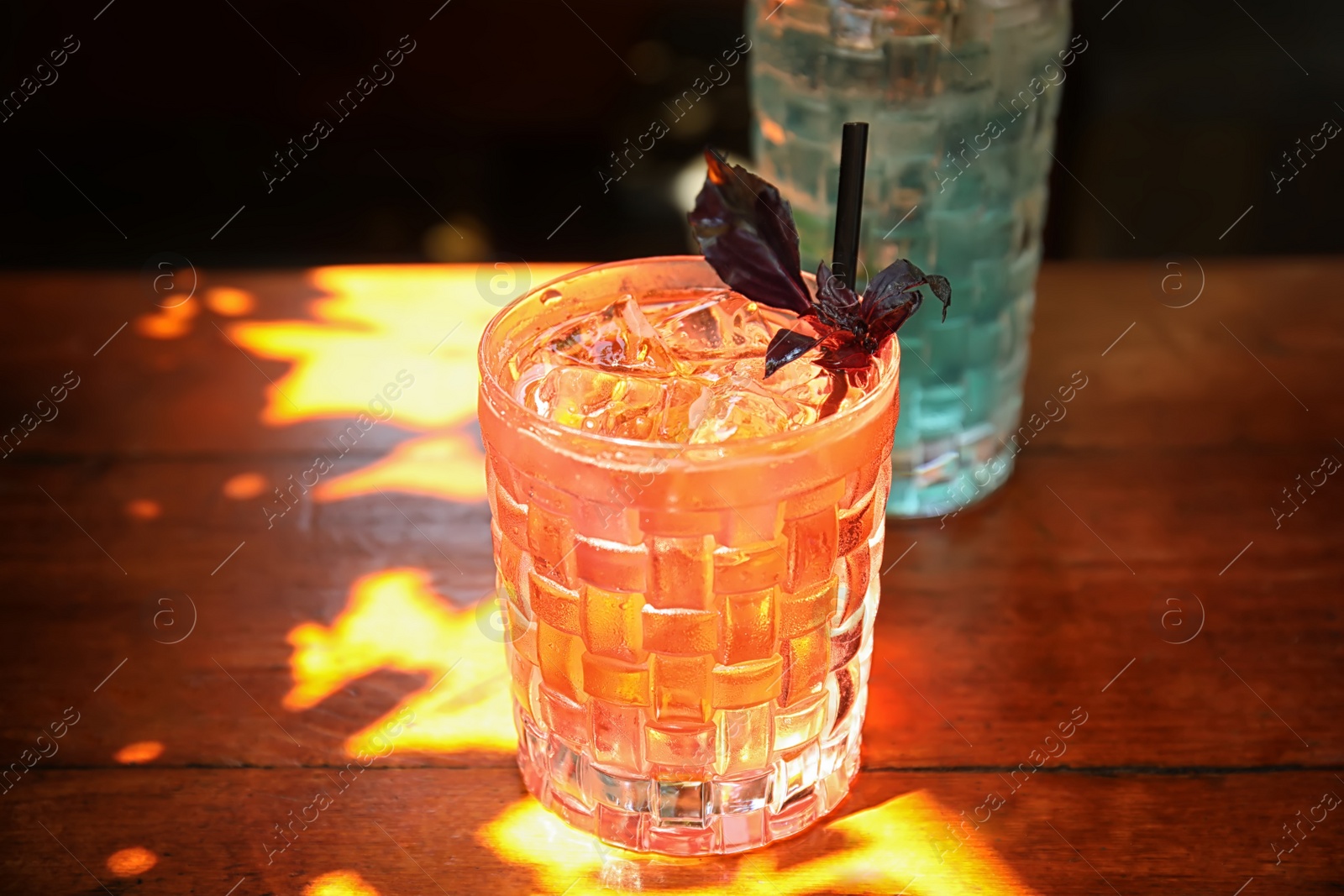 Photo of Glass with delicious cocktail and ice cubes on counter in bar