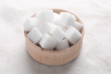 Different types of white sugar and bowl as background, closeup