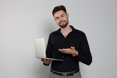 Photo of Handsome man in black shirt working with laptop on light grey background