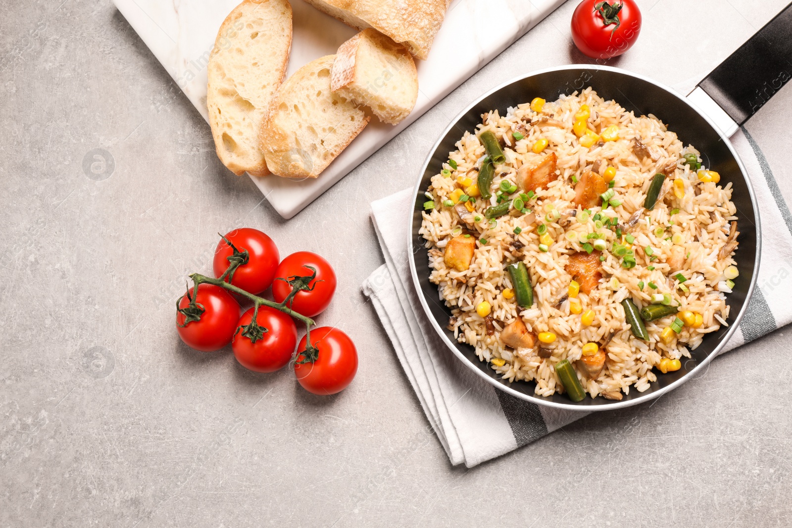 Photo of Delicious rice pilaf with chicken and vegetables on light grey table, flat lay