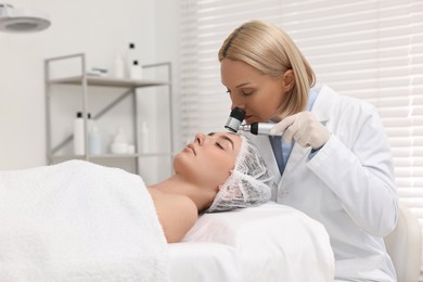 Dermatologist with dermatoscope examining patient`s face in clinic