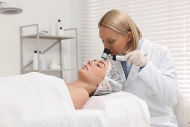 Photo of Dermatologist with dermatoscope examining patient`s face in clinic