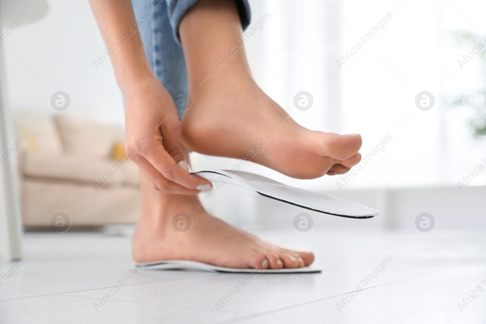 Photo of Woman fitting orthopedic insole at home, closeup