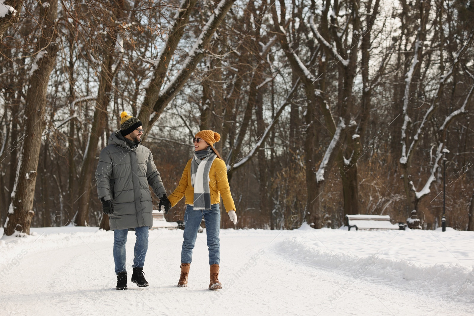 Photo of Beautiful happy couple walking in snowy park on winter day