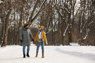 Beautiful happy couple walking in snowy park on winter day