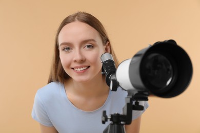 Happy astronomer with telescope on beige background