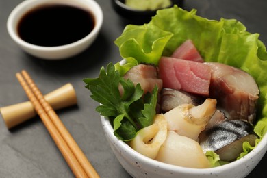 Delicious mackerel, squid and tuna served with lettuce, parsley and soy sauce on grey table, closeup. Tasty sashimi dish