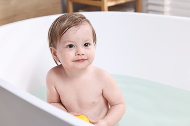 Cute little child bathing in tub at home