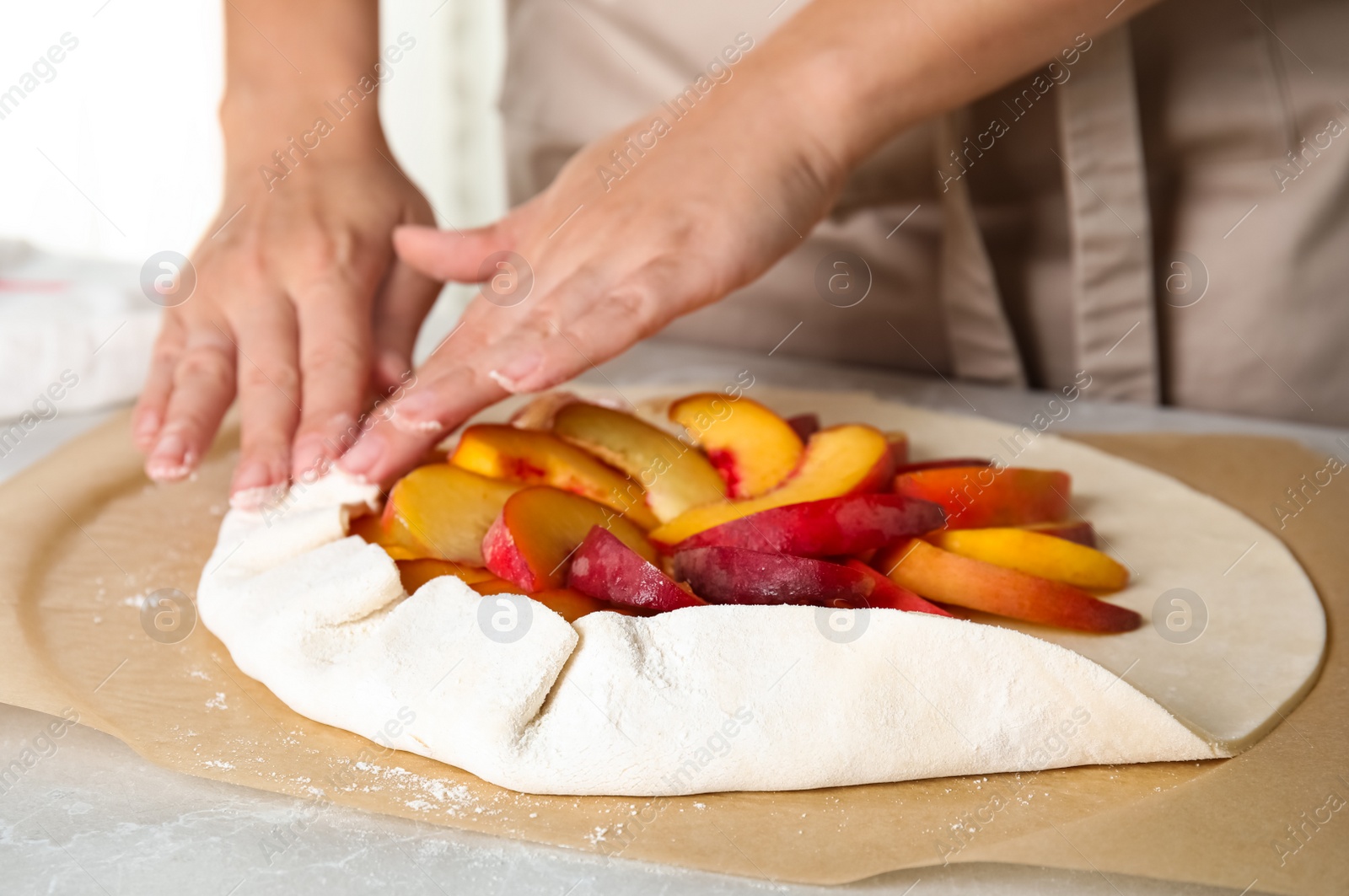 Photo of Woman making peach pie at kitchen table, closeup