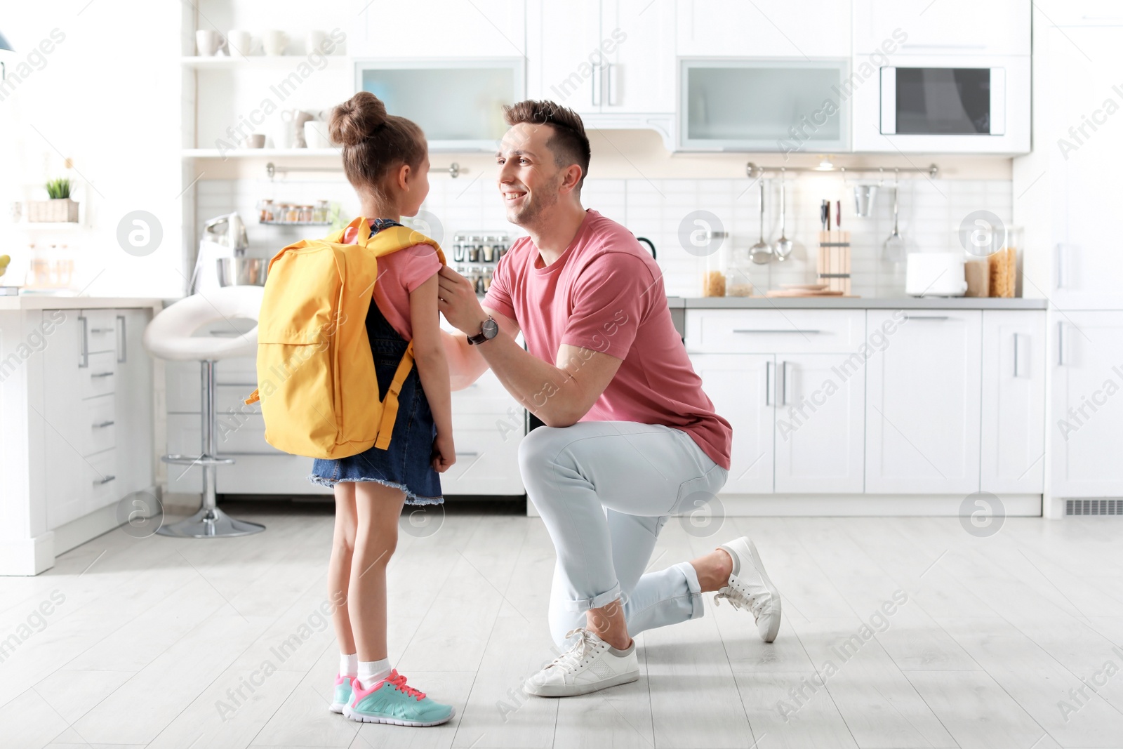 Photo of Young man helping his little child get ready for school at home