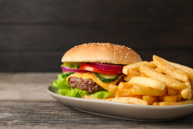 Photo of Delicious burger and french fries served on wooden table, closeup. Space for text