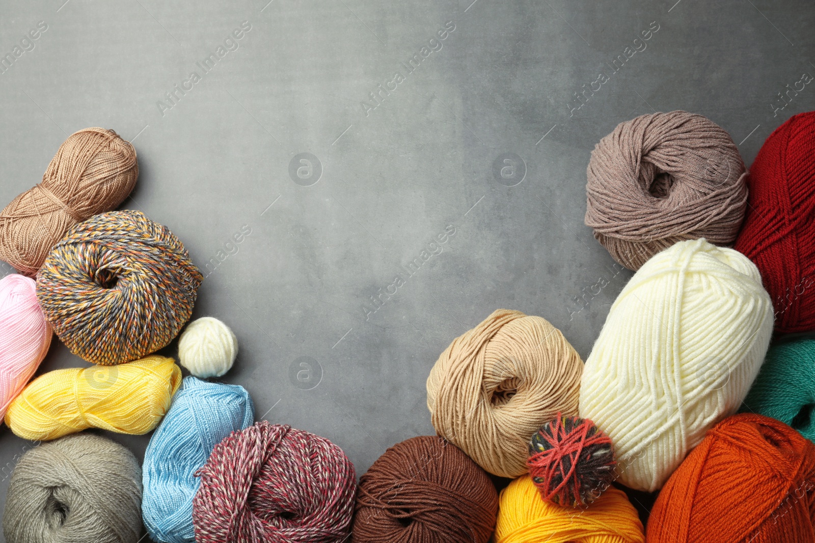 Photo of Different balls of woolen knitting yarns on grey background, flat lay. Space for text