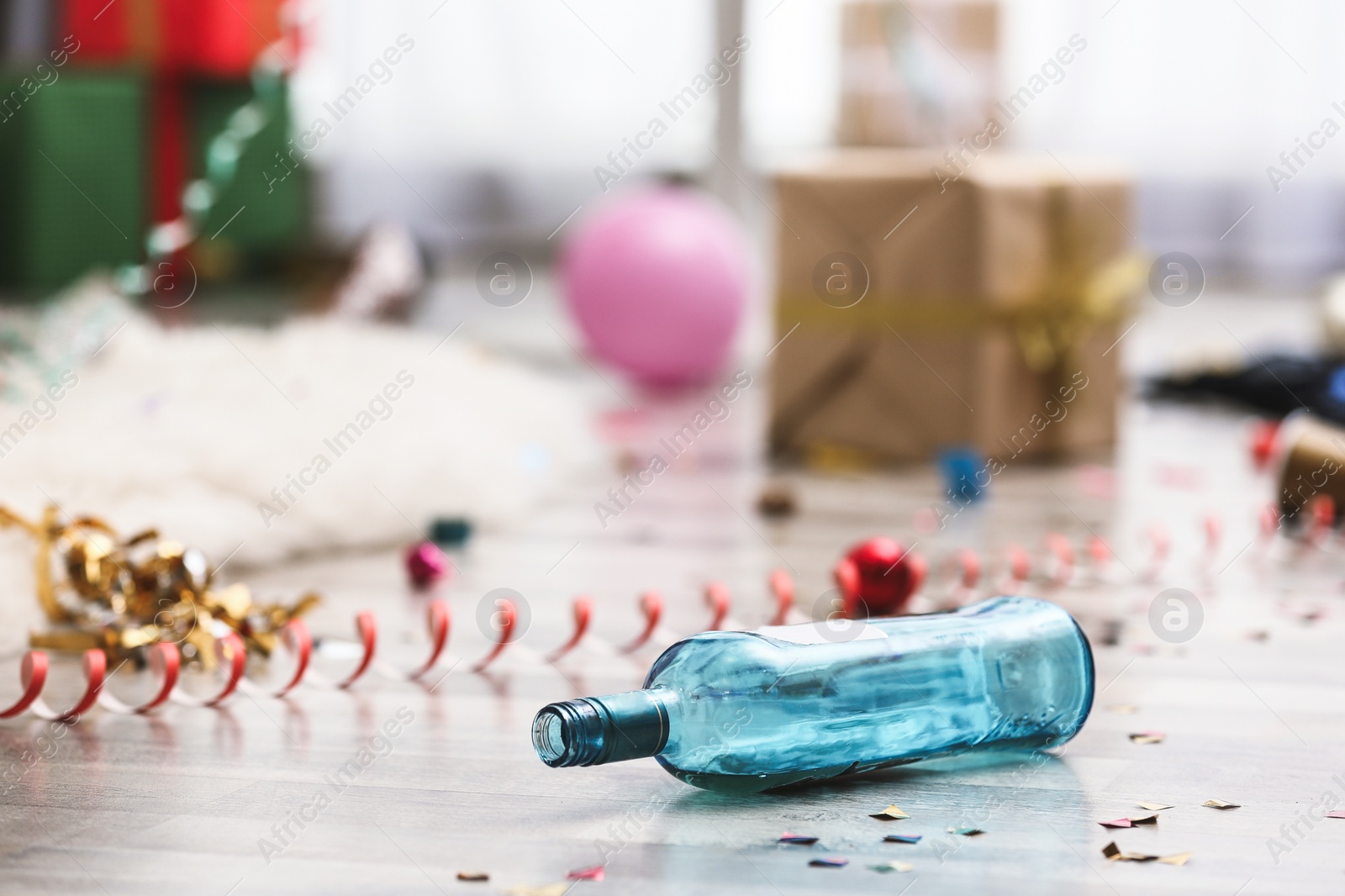 Photo of Empty bottle and confetti on messy floor. Chaos after party