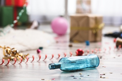 Photo of Empty bottle and confetti on messy floor. Chaos after party