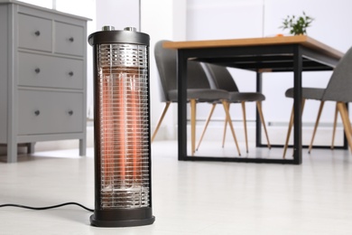 Modern electric heater on floor at home. Space for text