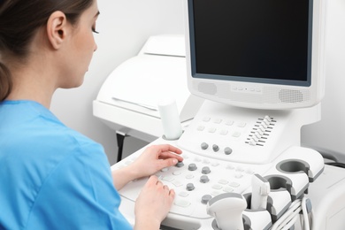 Sonographer operating modern ultrasound machine in clinic