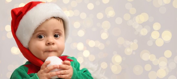 Cute baby wearing Christmas costume against blurred lights, space for text. Banner design