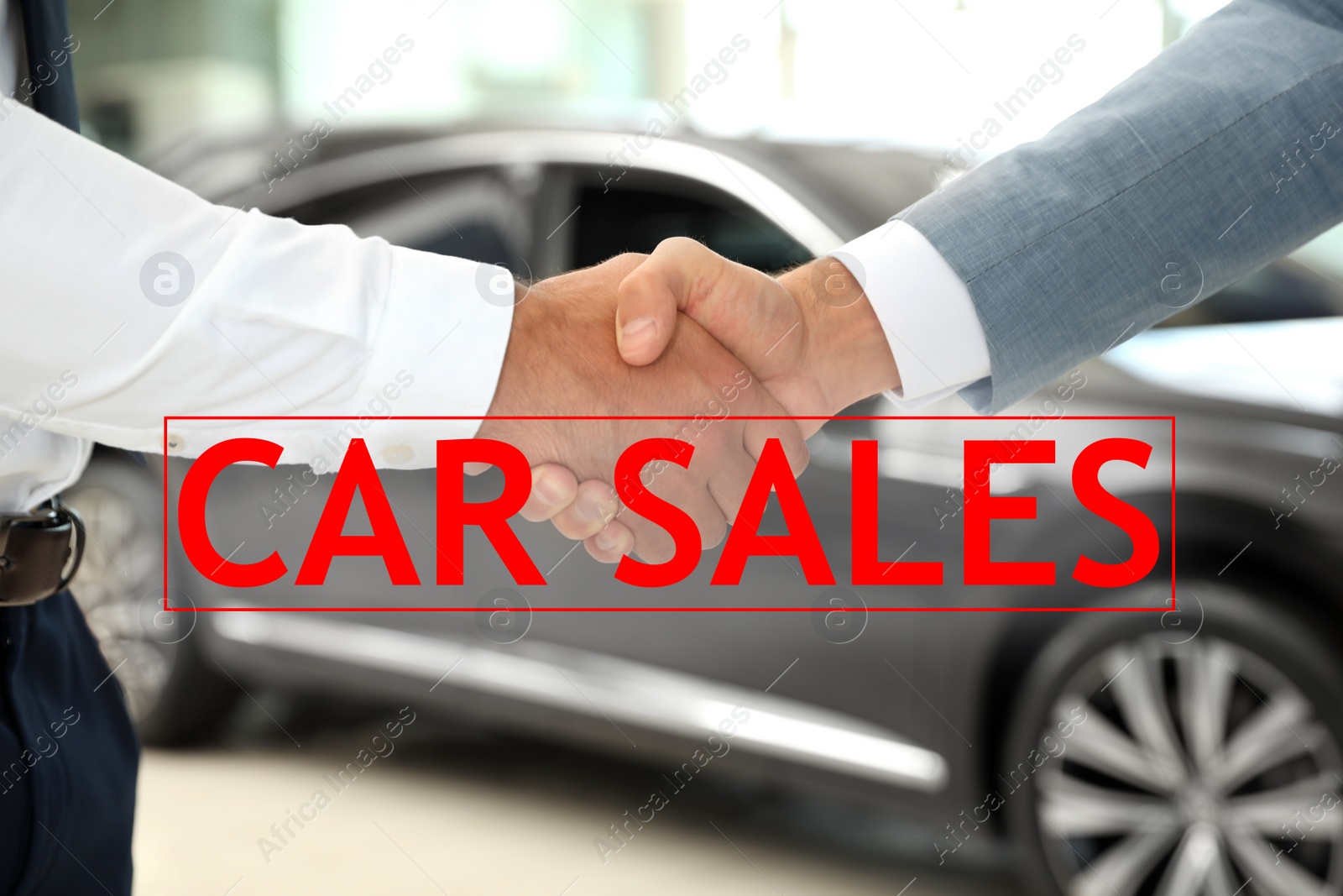 Image of Young salesman shaking hands with client in car dealership, closeup